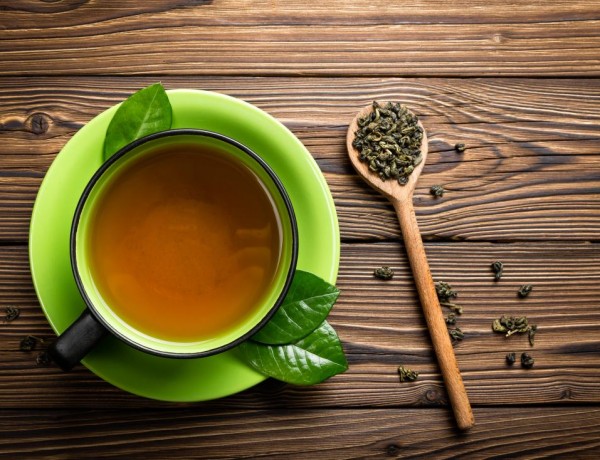 green-tea-in-cup-with-tea-leaves-on-wooden-spoon