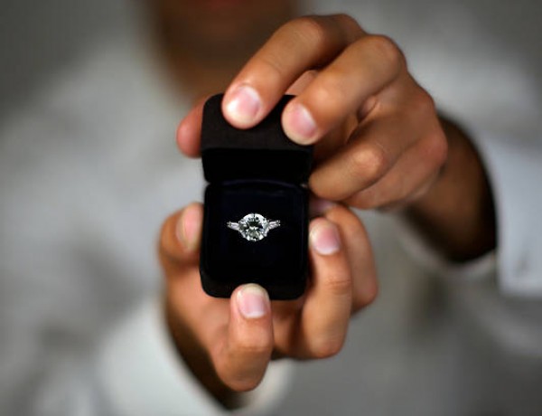 A man proposing and holding up an engagement ring